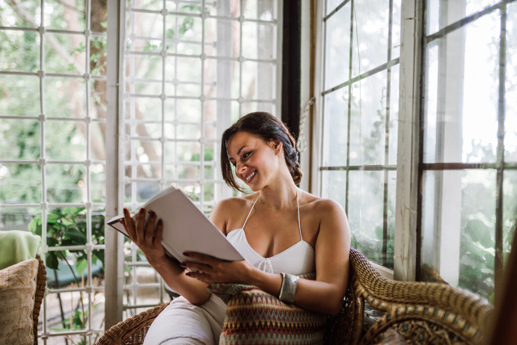 woman reading a book in a sunroom or conservatory exte
