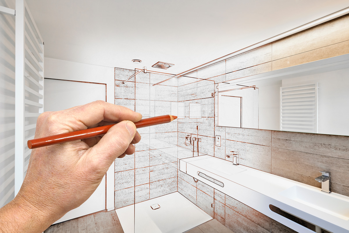 A person's hand drawing bathroom remodel plans with a brown colored pencil in Seattle.