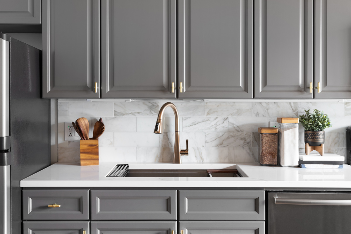 A kitchen with marble backsplash and grey cabinets in Seattle.