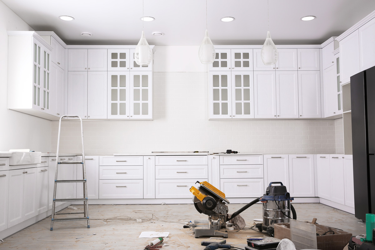 An all-white kitchen in Seattle is being remodeled with different tools on the floor.